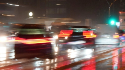 Die Lichter von Ampeln und Fahrzeugen spiegeln sich im Regen auf einer Straße. (Foto: Marcus Brandt/dpa/Symbolbild)
