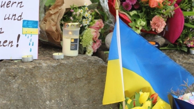 Am Gelände eines Einkaufszentrums, an dem zwei Männer aus der Ukraine getötet worden sind, wurden Blumen niedergelegt sowie eine kleine ukrainische Flagge aufgestellt. (Foto: Constanze Wilz/dpa)