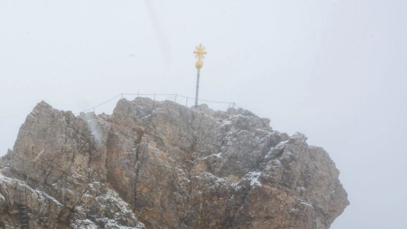 Nebelwolken umhüllen bei Schneetreiben auf der Zugspitze (2962 Meter) die verschneite Aussichtsplattform mit dem Gipfelkreuz. (Foto: Peter Kneffel/dpa/Archivbild)